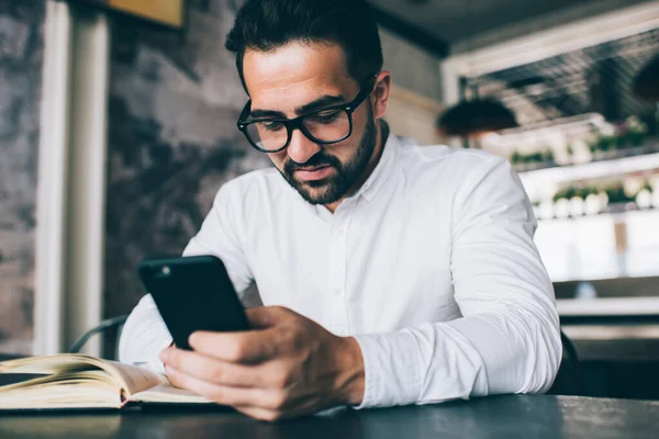 Prosperující Kavkazský Vousáč Brýlích Kontroluje Příjem Pošty Smartphone Zatímco Pracuje — Stock fotografie