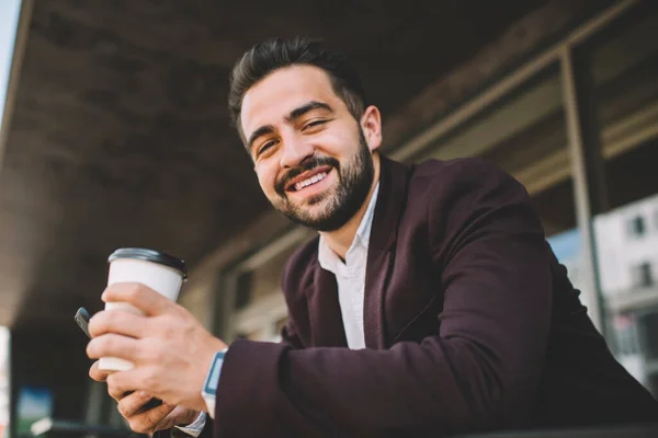 Happy bearded man in formal outfit looking at camera enjoying rest on break outdoors,portrait of handsome bearded young male manager holding coffee to go cup smiling satisfied with success caree