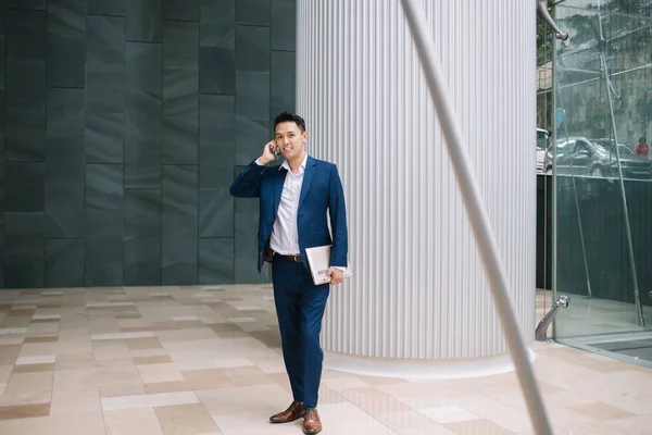 Pensativo Bonito Ásia Homem Elegante Terno Segurando Laptop Enquanto Falando — Fotografia de Stock