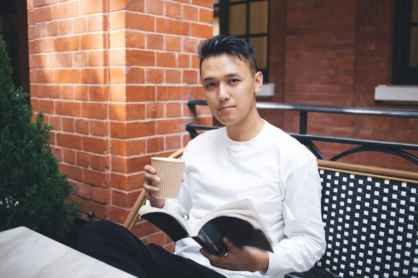 Серьезный Молодой Азиат Белой Рубашке Пьющий Кофе Читающий Любимую Книгу — стоковое фото