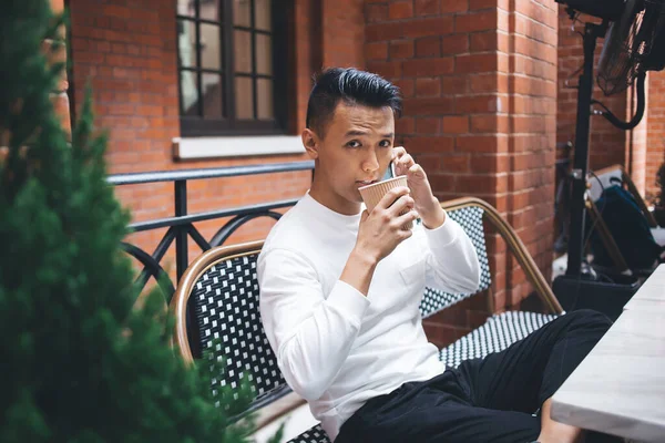 Young Focused Handsome Asian Male Looking Camera Speaking Smartphone While — Stock Photo, Image
