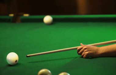Bilardo topları ve yeşil arka planda bir ıstaka ile el.