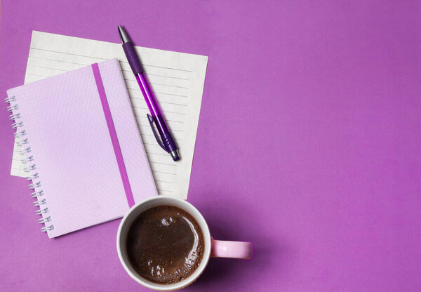 coffee, notebook and pen on a lilac background