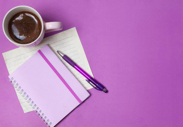 coffee, notebook and pen on a lilac background