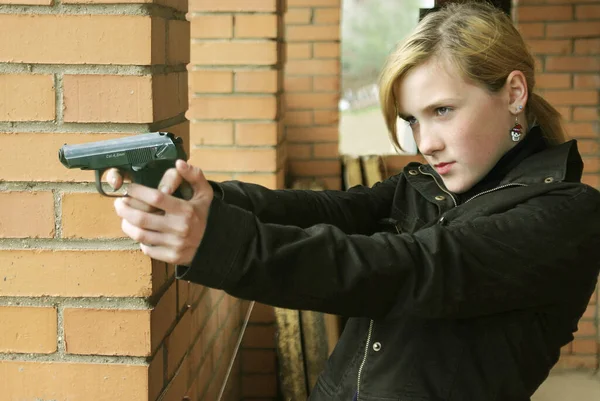 a teenage girl aims a gun