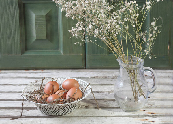 rural still life with flowers in a jug and chicken eggs