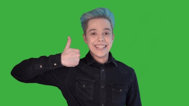 Молодий чоловік посміхається, показуючи себе на зеленому екрані. Гей з кольоровим волоссям — стокове відео