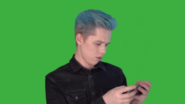 Young man holding mobile using mobile apps scratching his head green screen — Stock Video