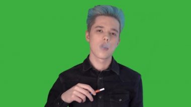 Elektronik sigara içen genç işadamı yeşil ekran kameraya bakıyor.