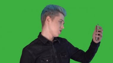 Genç ve çekici bir blogcu kameraya bakıyor ve yeşil ekranda konuşuyor.