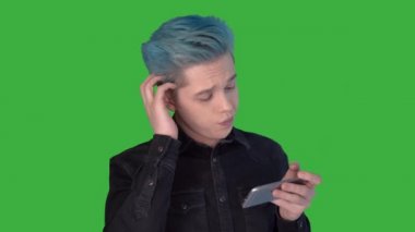 Genç adam mobil bir oyun oynuyor. Yeşil ekranda oyunlar oynanıyor.