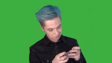Genç komik adam mobil bir oyun oynuyor. Duygular. Yeşil ekranda oyunlar oynanıyor.