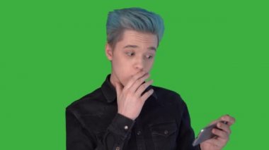 Mobil oyun oynayan şok olmuş genç bir adam. Yeşil ekranda Mutlu Oyunlar.