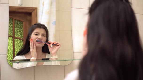Mladá žena čištění zubů pocit silné bolesti zubů dotýkání se její tváře detailní — Stock video