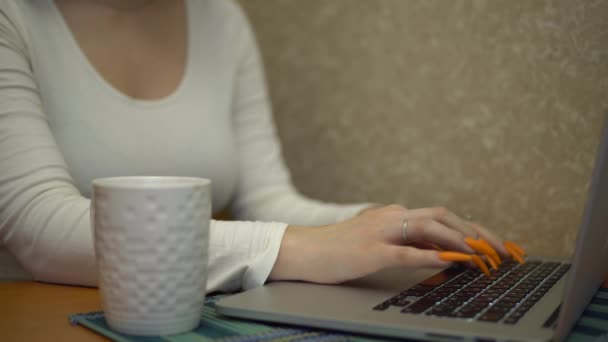 Mujer joven que trabaja en el ordenador portátil en la cocina escribiendo en el cuaderno maqueta de beber té — Vídeos de Stock