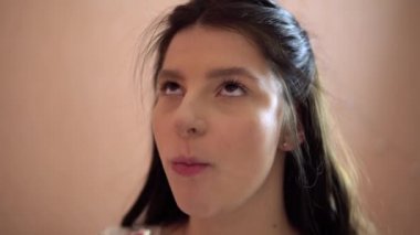 Aç gözlülükle çikolatalı pasta yiyen genç bir kadın kameraya bakıyor, koca ağızlı.