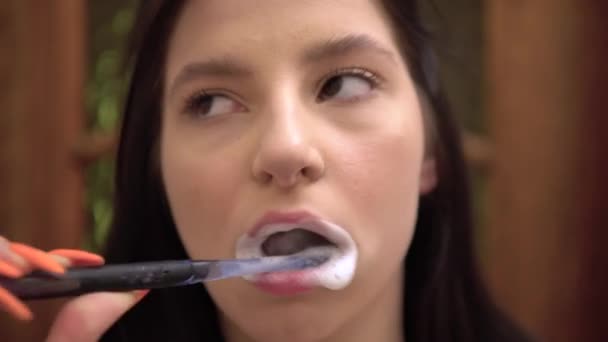 Молодая женщина при чистке зубов чувствует сильную зубную боль, касающуюся ее щеки — стоковое видео