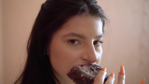 Młoda kobieta je ciasto czekoladowe z kremem patrząc na aparat fotograficzny, pełne usta — Wideo stockowe