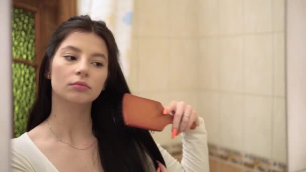 Junge Frau bürstet morgens lange Haare, die sich in Spiegelkämmen spiegeln — Stockvideo