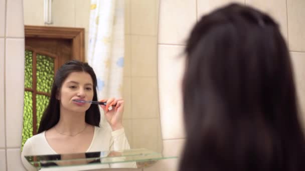 Mujer joven cepillándose los dientes Pasta de dientes. Espejos en el baño. Higiene oral — Vídeo de stock