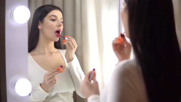 Красавица доверчивая девушка положила красную помаду перед зеркалом и восхищается собой — стоковое видео