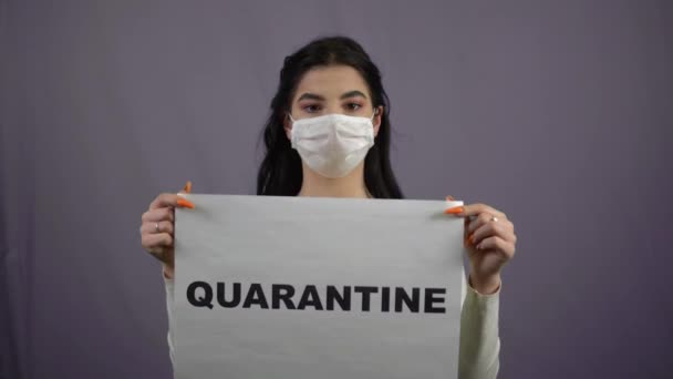 Donna in maschera medica che tiene segno di quarantena grigio backgroung coronavirus covid — Video Stock