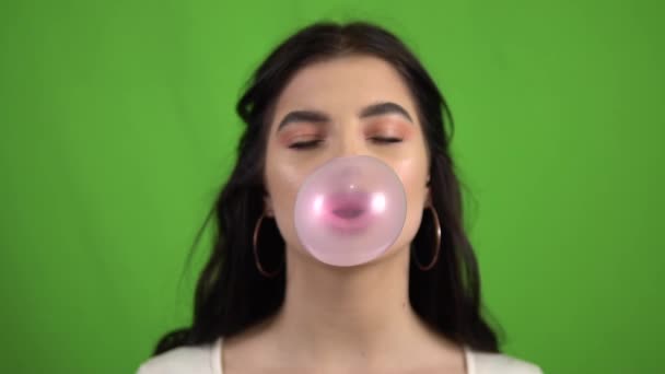 Sexy młoda kobieta dmuchanie bąbelki guma żucie guma na zielony ekran powolny ruch — Wideo stockowe