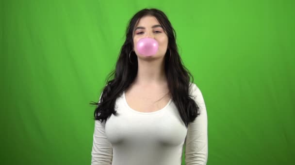 Girl chewing gum blowing bubble gum on green screen slow motion 4x — Stock Video