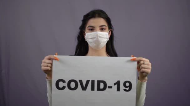 Mädchen in medizinischer Maske mit Quarantäne-Zeichen COVID-19 singen Coronavirus — Stockvideo