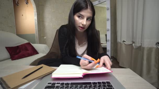 Девушка с помощью ноутбука изучения онлайн делать заметки писать эссе подготовительный экзамен — стоковое видео