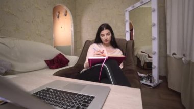 Öğrenci kız laptoptan notlar alıyor, çevrimiçi çalışıyor, serbest çalışıyor, yazı yazıyor.