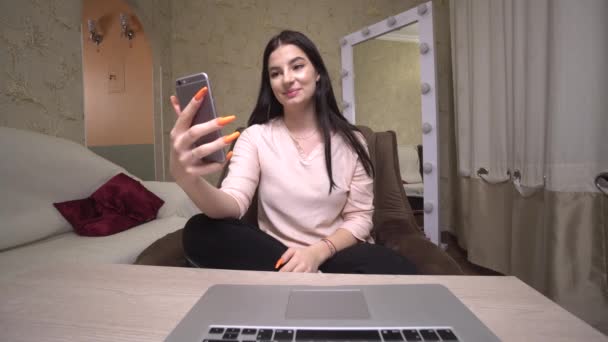 Chica sosteniendo teléfono inteligente mirando la cámara animada conversación en videollamada — Vídeos de Stock