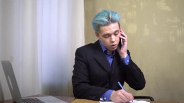 Genç ofis çalışanı telefonla konuşuyor, yazıyor, formu dolduruyor.