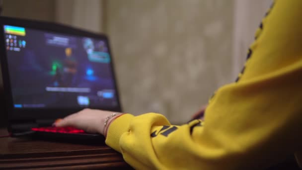 Menina gamer jogar jogo de vídeo, atirador, laptop de jogos, visão traseira sobre o ombro — Vídeo de Stock