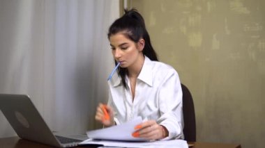 Odaklanmış genç ofis çalışanı, sekreter dizüstü bilgisayara bakıyor notlar alıyor