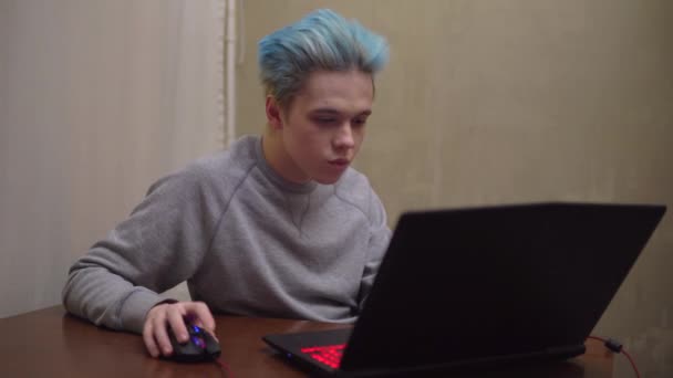 Giocatore che gioca nel videogioco online sul computer portatile, focalizzata sul gioco, capelli blu — Video Stock