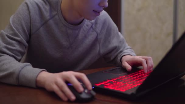 Игра в видеоигры на игровом ноутбуке, командный шутер, красная неоновая клавиатура — стоковое видео