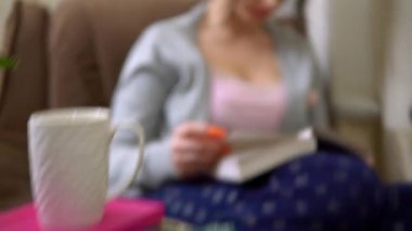 Kitap okuyan genç bir kadın, ev konforu, evinde dinlenme koltuğu,