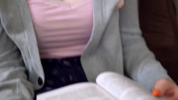 Милая молодая женщина читает книгу, руки переворачивая страницу близко, домашний комфорт — стоковое видео