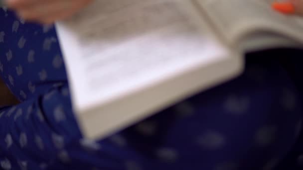 Νεαρή γυναίκα διαβάζει βιβλία. Γυναικεία στροφή σελίδες στο βιβλίο, άνεση στο σπίτι, πολυθρόνα — Αρχείο Βίντεο