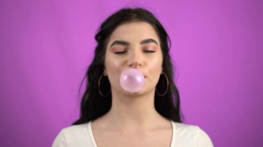 Esmer kız yeşil ekranda pembe sakız üflüyor.