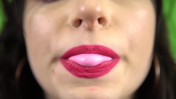 Сексуальна дівчина дме рожеву жувальну гумку на зеленому екрані рожева помада — стокове відео