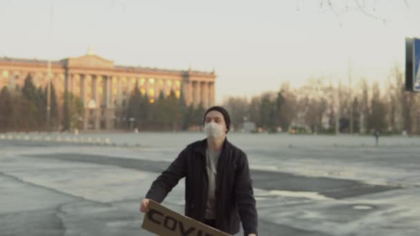 Young man holding COVID-19 poster on empty city area, pandemic, quarantine — Stock Video