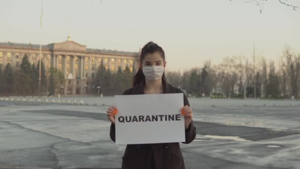 Жінка тримає знак карантину на вулиці на порожній ділянці, ковід-19, коронавірус, маска — стокове відео
