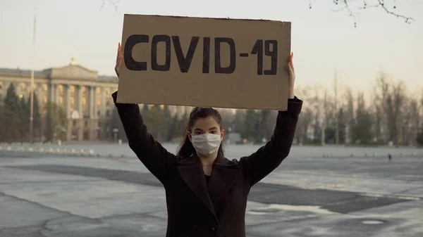 소녀가 COVID-19 표지판을 길 위의 텅 빈 지역에 걸고 있다 격리, 코로나 바이러스, 마스크 로열티 프리 스톡 이미지