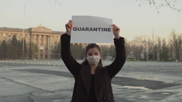 Mulher em máscara protetora na rua mantenha cartaz de quarentena. Coronavírus, COVID-19 — Vídeo de Stock