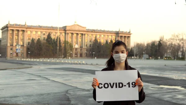 Genç kadın covid-19 işareti boş alan caddesinde, karantina salgını maskesi
