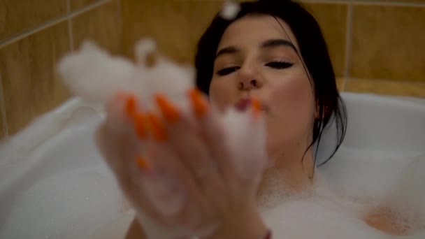 Beauty girl blows to foam in bubble bath, relaxing cozy romantic home atmosphere — Stock Video