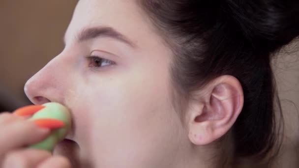 Mladá dívka míchání nadace s houbou, make-up, vizáž umělec zblízka tvář — Stock video