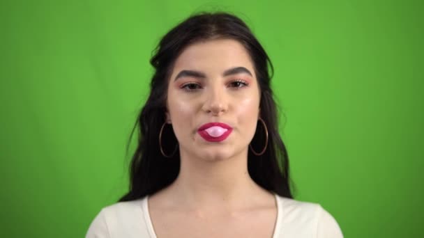 Sexy schoonheid meisje kauwgom, blazen bubbels kauwgom op groen scherm — Stockvideo